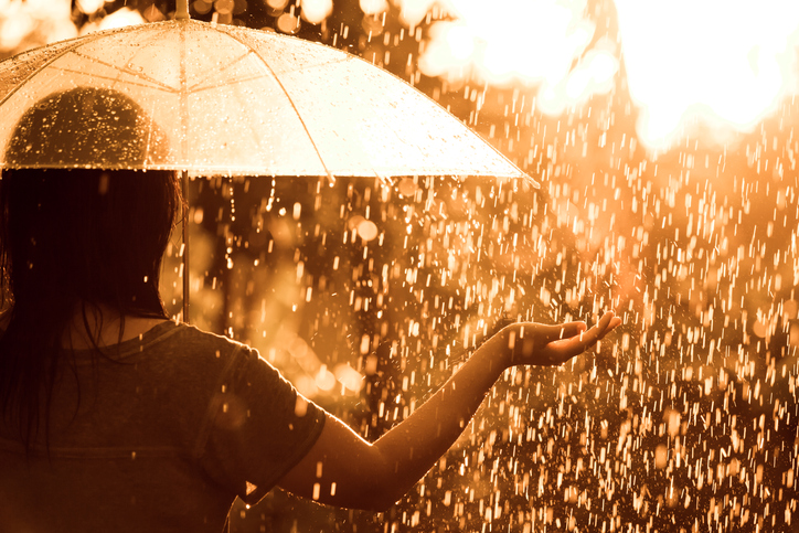 A woman holds out her hand to feel the rain coming down.
