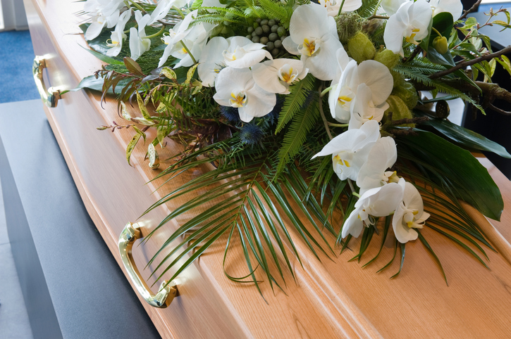 A bouquet of white flowers sits atop a closed coffin.