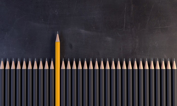 Yellow pencil standing out next to black pencils