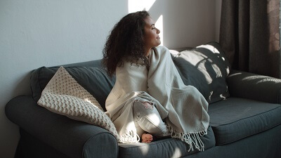 Woman sitting under a blanket at home, relaxing