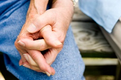 A close-up of a couple's hands clasped as they are seated side-by-side