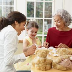 Little girl has tea party at table with mother and grandmother