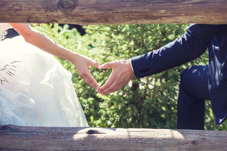 Hands of couple in wedding clothing form heart