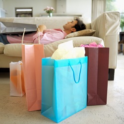 A man lays on the couch surrounded by shopping bags